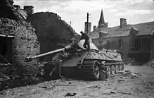 Soldats britanniques inspectant un char allemand Tigre royal mis hors de combat dans une rue du Plessis-Grimoult.