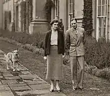 Photographie en noir et blanc d'une femme et d'un homme se promenant dans un jardin.