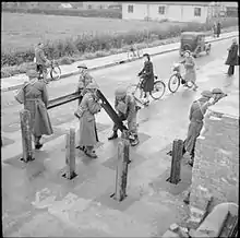 Des soldats de la Home Guard installent des poutrelles métalliques verticalement dans le sol