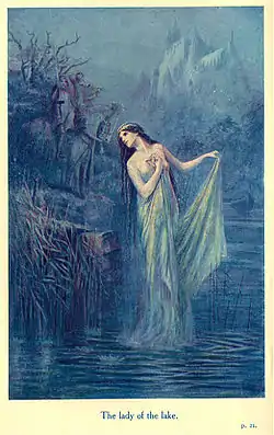 Femme aux cheveux bruns, portant une couronne de fleur et une longue robe bleu dans une rivière. On distingue au loin dans la brume un chevalier en armure et un château.
