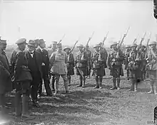Photo en noir et blanc d'un groupe d'hommes militaires se tenant devant une division d'infanterie.