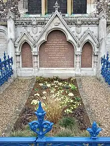 Tombe entourée par une barrière bleue avec une pierre tombale de style gothique