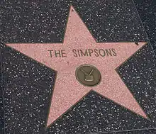 Photographie d'une étoile rose sur un trottoir de marbre. Il est écrit dessus « The Simpsons ».