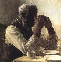 Vieil homme afro-américain priant à une table.