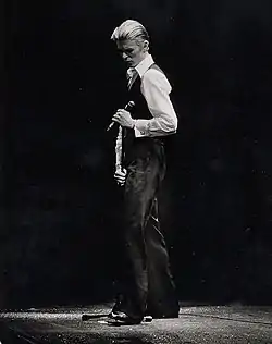 Photo en noir et blanc d'un homme de trois-quarts-dos élégamment vêtu.