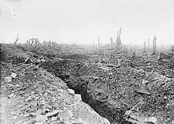 Photo noir et blanc d'un long fossé étroit dans un champ de terre dévasté.