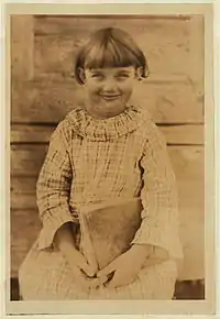 Photo d'enfant souriante, assise, de face