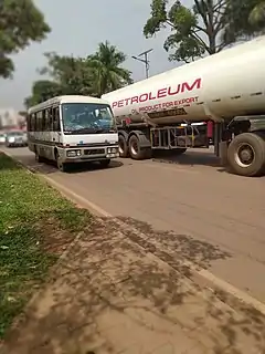 Photographie couleur d'un camion-citerne pétrolier roulant sur une route africaine.