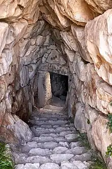 Galerie en pierre descendant, au moyen d'un escalier, vers une porte en pierre