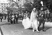Cliché noir et blanc dans avenue. Homme : uniforme slave. Femme : en mariée avec longue traîne. Cortège en apparat.