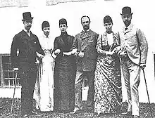 Photographie en noir et blanc d'un groupe de trois hommes et trois femmes se tenant par le bras.