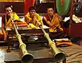 Moines bouddhistes tibétains soufflant les longues cornes et tambourinant, monastère de Tharlam, cérémonies de clôture.