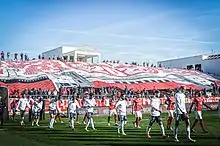 Photographie du Pesage Est au Stade des Costières et du tifo des Gladiators Nîmes 1991, groupe de supporters du Nîmes Olympique.