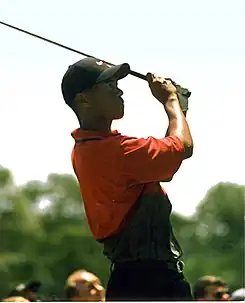 Un golfeur avec un club en main regarde au loin.