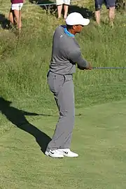 Le golfeur termine son geste avec son club à l'horizontal et les yeux vers sa balle.