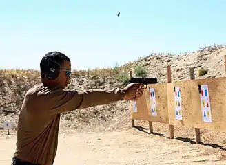 Un homme tenant une arme à la main dans le désert.