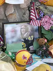 Autour d'une photo encadrée de Pat Tillman, plusieurs objets pour célébrer sa mémoire : des fleurs, un casque, une peluche et un drapeau américain.