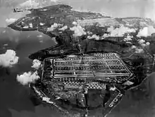 Photos en noir et blanc d'une base militaire de grande envergure en bord de mer.