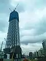 Photo couleur d'une tour métallique en construction, sous un ciel nuageux.