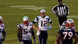 Tom Brady avec la main sur la hanche pendant une rencontre de football américain.