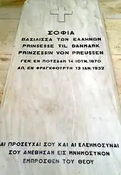 Pierre tombale ornée d'une croix grecque et d'inscriptions.