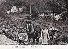 Photo d'un homme dirigeant un cheval qui tracte une charge sur un chemin de fer.