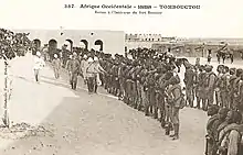 Photographie noir et blanc de divers hommes blancs inspectant des troupes coloniales.
