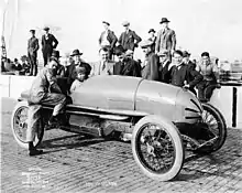 Tommy Milton et sa Frontenac avant le départ -puis la victoire- lors de l'Indy 500 1921. À sa droite Barney Oldfield, à sa gauche Louis Chevrolet (en sombre avec moustache).