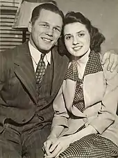 Photographie en noir et blanc d'un couple en costumes.