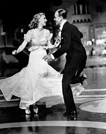 Une femme en robe et un homme en costume qui dansent.