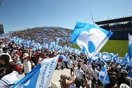 Photo de supporters dans un stade agitant des drapeaux bleu et blanc