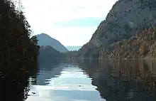 Un lac entouré de collines boisées et de montagnes.