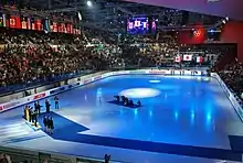 La patinoire, avec un podium, éclairée par une lumière bleue.