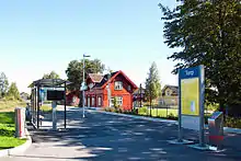 à gauche le quai de la halte de Torp avec son abri et au centre l'ancien bâtiment en bois, peint en rouge, de l'ancienne gare de Råstad