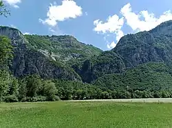 Vue du torrent de l'Épine à Magland dans la cluse de l'Arve : le Funiflaine serait passé à l'emplacement de la ligne électrique qui s'élève vers la droite ; la ligne électrique soutenue par les pylônes rouge et blanc alimente quant à elle les Carroz d'Arâches sur la gauche.