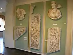 Deux boucliers exposés en compagnie d'éléments de décor architecturaux en marbre.