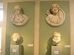 Deux boucliers exposés avec des têtes sculptées.