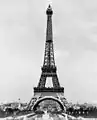 Tour Eiffel en acier construite pour l'Exposition universelle de Paris de 1889 célébrant le centenaire de la Révolution française. Architecture affirmée par des arcs rajoutés à sa base.