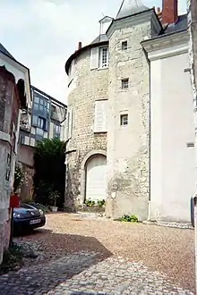 Photographie en couleurs d'une tour ronde accolée à un bâtiment à étage.