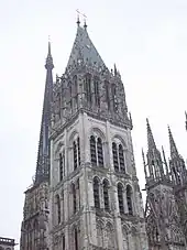 Photographie noir et blanc des derniers étages et du couronnement d'une tour.
