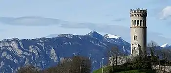 Panorama en couleurs d'une tour médiévale à droite et d'une ligne de crêtes montagneuses à gauche.