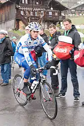 Photo d'un coureur cycliste sur son vélo devant plusieurs spectateurs.
