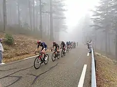 Rythme imposé par l'équipe Inéos en tête de peloton dans la montée vers le Chalet Reynard, dans le brouillard à environ 7 km de l'arrivée.