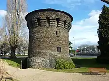  Photographie d'une tour isolée en schiste, coiffée d'un toit d'ardoise.