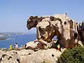 Vue latérale du Capo d'Orso avec des touristes donnant l'échelle du rocher.