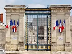 Photographie en couleurs d'une grille de portail monumentale.