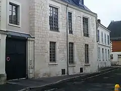 Photographie en couleurs de la façade d'une maison avec des baies en arc brisé murées.