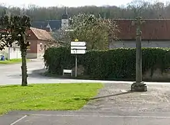 Vue de l'église depuis la place du village avec sa croix de pierre.