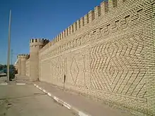 Mur avec des tourelles et motifs en briques.