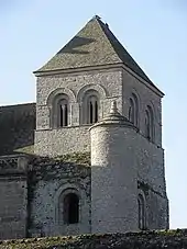 Une tour en architecture romane. On voit deux niveaux ; le premier est ouvert par une baie en plein cintre, le second par deux baies géminées également en plein cintre. À l'angle de la tour, il y a une tourelle d'escalier.